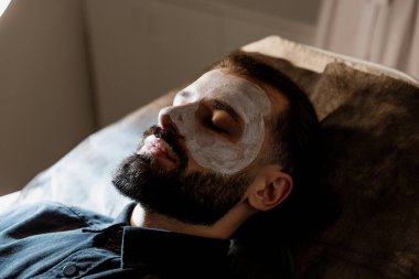 Güzellik uzmanı, spa 'daki yaşlı bir adamın yüzüne masaj uygular.