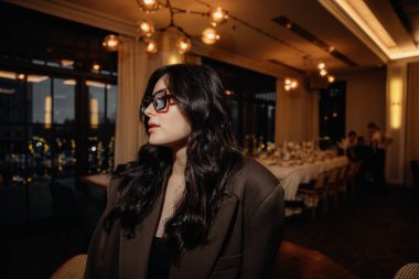 Şık bir esmerin, büyük beden bir takım elbise içinde, bir restoranın arka planına dayanan ve fotoğraf için şık poz veren şık bir esmer fotoğrafı.