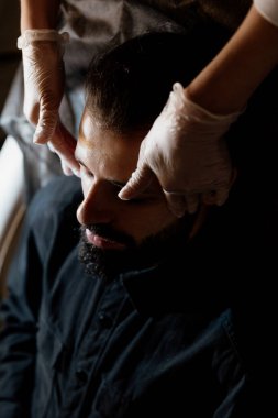 Şık sakallı adam güzellik salonunda yüz masajı yaptırıyor.