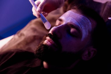 Güzellik uzmanı, spa 'daki yaşlı bir adamın yüzüne masaj uygular.