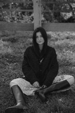 Çok doğal ve zarif bir kadın, doğanın arka planına karşı bir fotoğraf için poz verir, kadınlığını vurgulayan şık kıyafetler giyer.