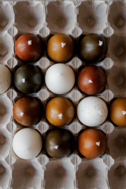 Boyalı tavuk yumurtası şeklinde şık mumlar. Paskalya teması, paskalya yumurtası mumları kağıt yumurta tepsileri içinde minimalist bir arka plan, Paskalya estetiği