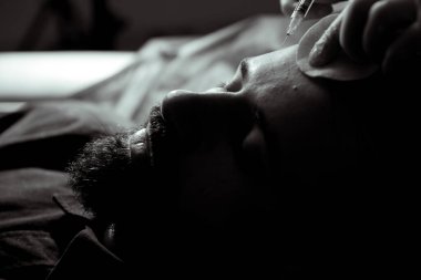 Güzellik uzmanında çeşitli güzellik tedavileri gören rahat genç bir adam sakallı bir adamın portresi güzellik iğneleri ve yüz maskeleri olan bir adam.