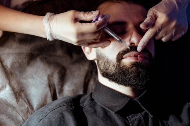 Güzellik uzmanında çeşitli güzellik tedavileri gören rahat genç bir adam sakallı bir adamın portresi güzellik iğneleri ve yüz maskeleri olan bir adam.