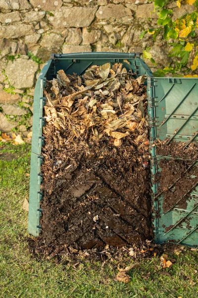 stock image Outdoor compost bin was opened to extract mature compost formed in the down part.The compost bin is placed in a home garden to recycle organic waste produced in home and garden.