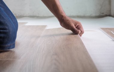 Bir teknisyen döşemeyi köpüğe yerleştirmeden önce döşemek için lüks vinil döşeme döşemeleri kuruyor..