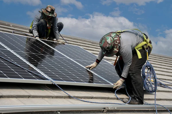 technicians are installing solar panels on the roof to use solar energy to power the building.