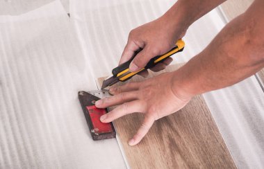 Bir teknisyen, köpüğü düzleştirmeden önce zemini kesmek için vinil döşeme kiremitlerini kesiyor..