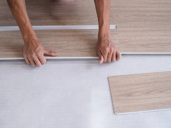 stock image A technician is cutting luxury vinyl floor tiles with a cutter to lay the floor before placing it on the leveling foam.