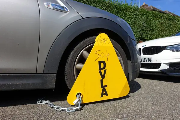 stock image DVLA wheel clamp on untaxed BMW Mini vehicle