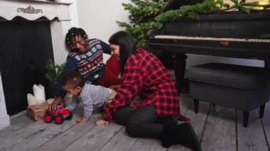 Noel arifesi. Bebek emekliyor ve Noel 'de oyuncak bir araba ve ebeveynlerle oynuyor. Yüksek kalite 4k görüntü