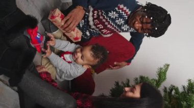 Dikey - Genç çok ırklı aile Noel ağacının yanında bebek, oyuncak araba ve hediyelerle eğleniyor. Mutlu aile kavramı. Yüksek kalite 4k görüntü