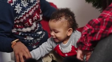 Annem ve babamın Noel ağacının altında oyuncak bir arabayla oynadığı şirin bir bebek. Yüksek kalite 4k görüntü