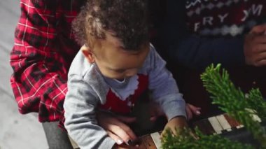  Genç çok ırklı aile Noel ağacının yanında bebek, oyuncak araba ve hediyelerle eğleniyor. Mutlu aile kavramı. Yüksek kalite 4k görüntü