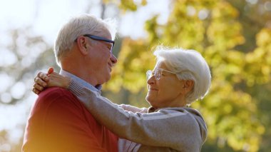 Senior married couple hugging and looking at each other in sunny autumn nature. High quality photo
