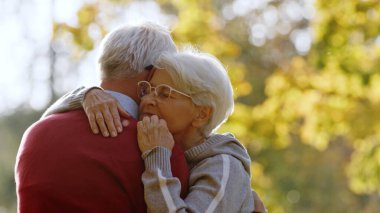 Two loving grey-haired people hugging outdoor in autumn nature. High quality photo