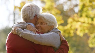 Married grey-haired couple hugging outdoor. High quality photo