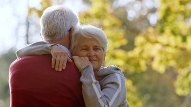 Retired grey-haired woman hugging her husband outdoor. High quality photo