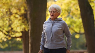 Older grey-haired woman excercising in the park . High quality photo