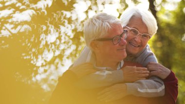 Older smiling man and woman hugging outdoor in nature. High quality photo