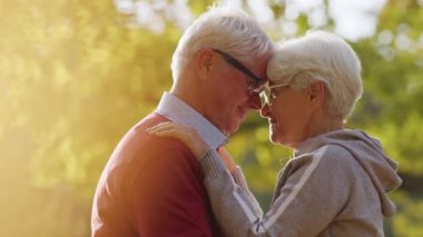 Senior grey-haired man and woman in love hugging and touching foreheads. High quality photo