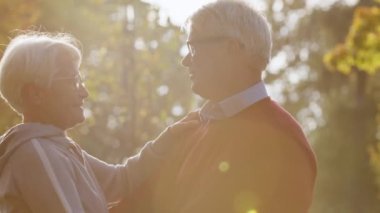 Smiling healthy old couple dancing in the park on a sunny day. High quality photo