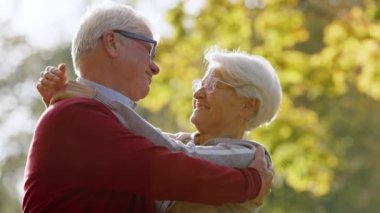 Senior married couple hugging and looking at each other in sunny autumn nature. High quality photo