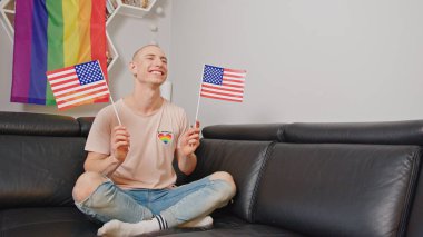 Smiling gay man waving UK flag in his apartment. High quality photo