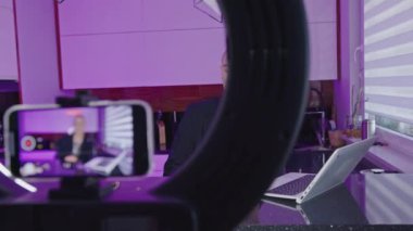 Man creating video content in a studio, filming himself with a phone on a tripod. High quality 4k footage