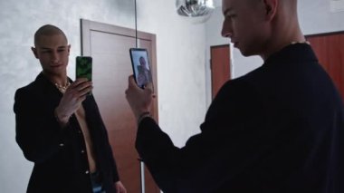 Bald gay man with bare torso taking mirror selfie with a phone . High quality 4k footage