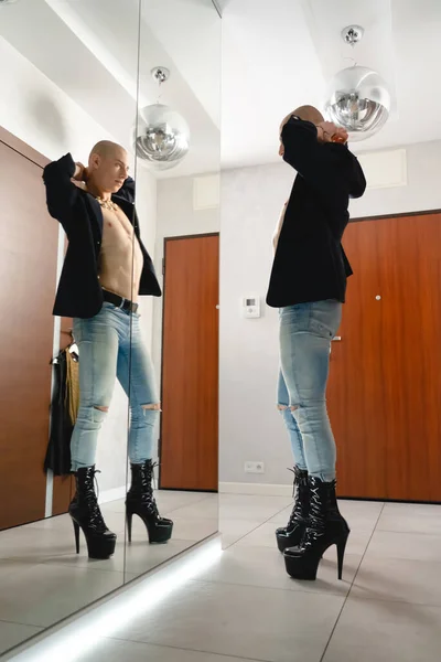 Low angle view of Gender fluid man with bare torso in high heels in front of a mirror. High quality photo