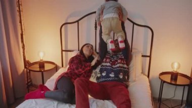 African American man lifting his biracial toddler son up in the air on a bed. High quality 4k footage