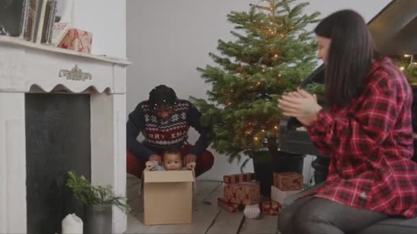 父はクリスマスの床の段ボール箱に彼の幼児の息子を押す 高品質4K映像 — ストック動画