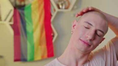 young handsome man posing for the camera in front of LGBT flag on the wall, closeup. High quality 4k footage