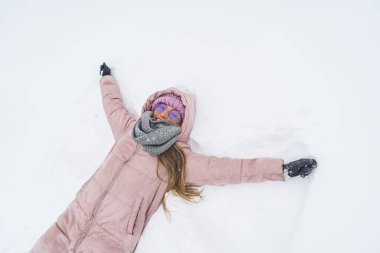 young woman in the snow making a snow angel, winter and snow concept medium shot. High quality photo