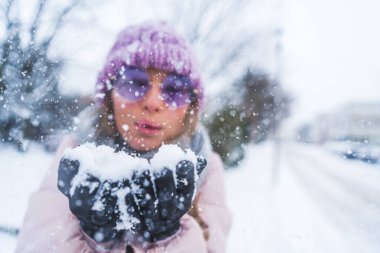 medium closeup shot of a woman blowing the snow on her hands, winter concept. High quality photo