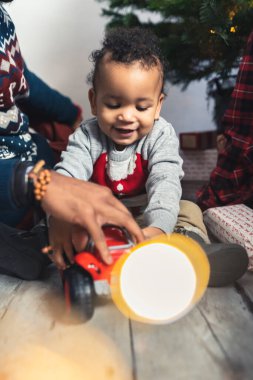 Afro-Amerikalı şirin bir çocuğun ailesiyle araba çalarken, arka planda dikey çekimde Noel ağacı. Yüksek kalite fotoğraf