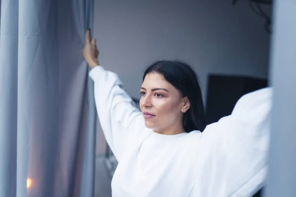 Kafkasyalı Bir Kadının Perdeleri Indirip Pencereden Içeri Bakarken Orta Ölçekli — Stok fotoğraf