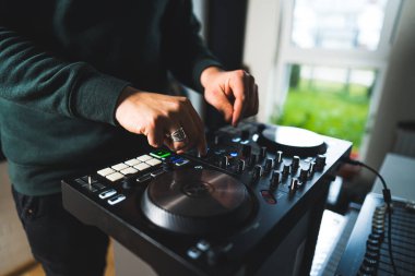 Genç adam ses mikserini ve sentezleyicisini bir ev stüdyosunda kullanıyor, yakın çekim müzik konsepti. Yüksek kalite fotoğraf