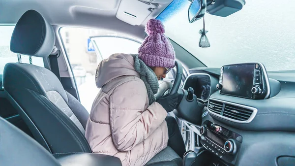 女の子は雪に覆われた車の中に座ってそれがオンになるのを待っている 高品質の写真 ロイヤリティフリーのストック画像