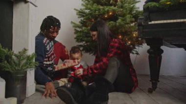 Anne ve baba Noel ağacının önünde küçük oğullarıyla oturup hediyelerle oynuyorlar. Yüksek kalite 4k görüntü