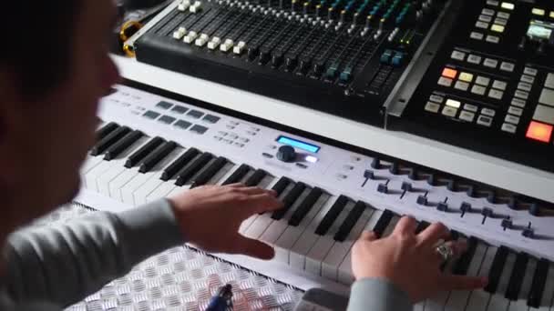 音のシンセサイザーと音楽のコンセプトで電子ピアノを演奏している男のバックビュー 高品質4K映像 — ストック動画