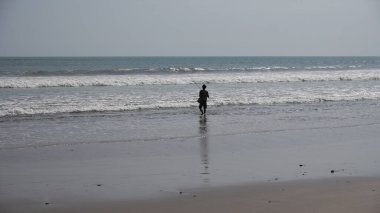 Sahilde siyah elbiseli bir adam.