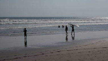 İnsanlar gün batımında denizde yürüyorlar.
