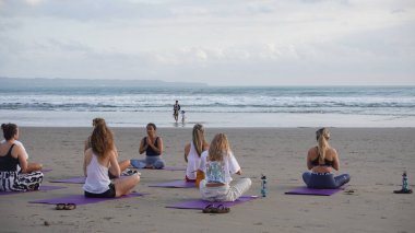 Sahilde yoga yapan bir grup genç.