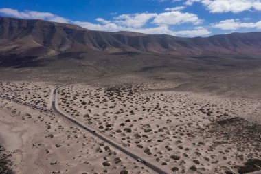 Kumlu ve volkanik çölün ortasındaki boş yolun manzarası. Kanarya Adaları, Lanzarote. Caleta de Famara 'ya bakın