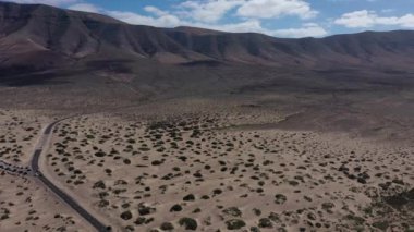 Kumlu ve volkanik çölün ortasındaki boş yolun manzarası. Kanarya Adaları, Lanzarote. Caleta de Famara 'ya bakın