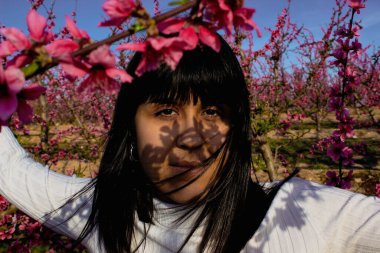 İspanya, Lleida 'da, yüzünü gölgeleyen güzel pembe şeftali çiçeklerinin arasında beyaz bir kadın..