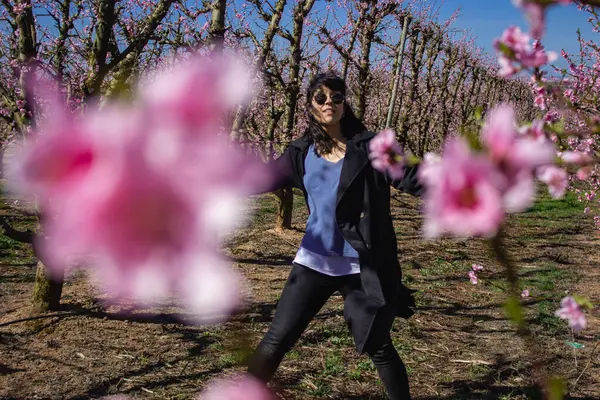 Woman walking through fields of flowering peach trees in spring through the beautiful fields of Aitona, Lleida.