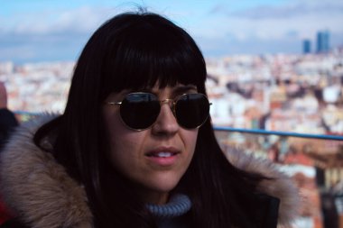 Güneşli bir kış gününde güneş gözlükleriyle poz veren güzel Avrupalı kadın Madrid arka planında